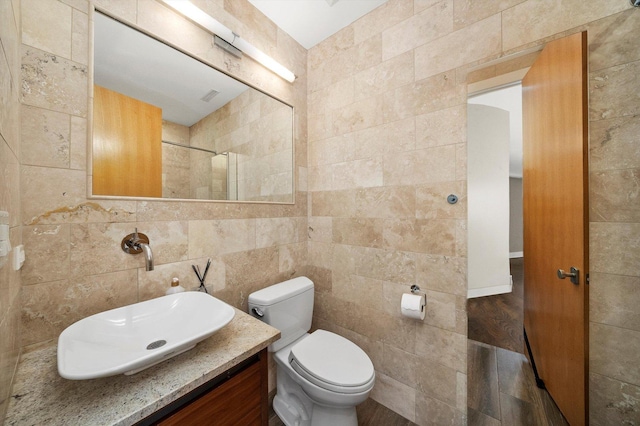 bathroom with tile walls, toilet, and vanity