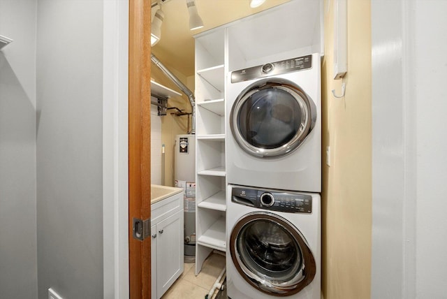 washroom featuring water heater, light tile patterned flooring, laundry area, and stacked washer / dryer