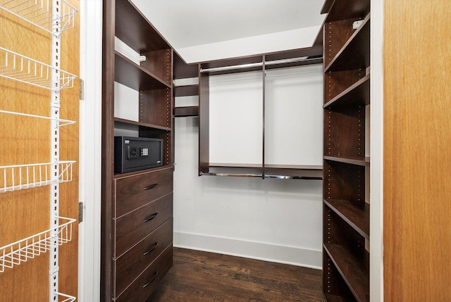 walk in closet with dark wood-style floors