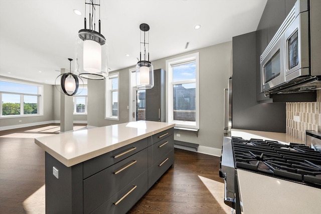 kitchen with a kitchen island, dark wood-style flooring, stainless steel appliances, decorative backsplash, and light countertops