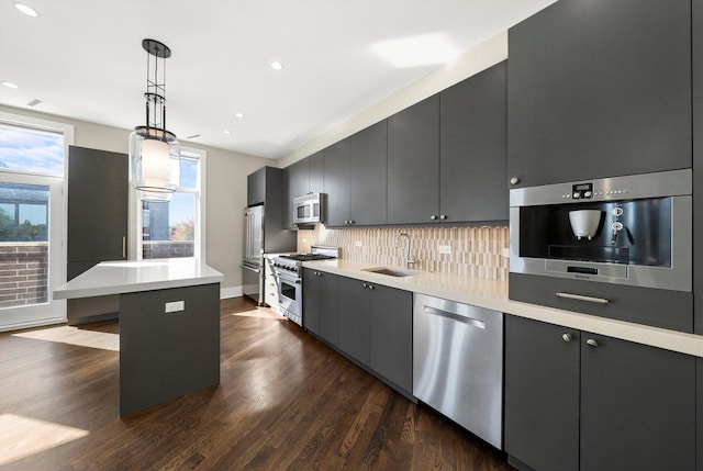 kitchen with a sink, decorative backsplash, high end appliances, and dark wood-style flooring