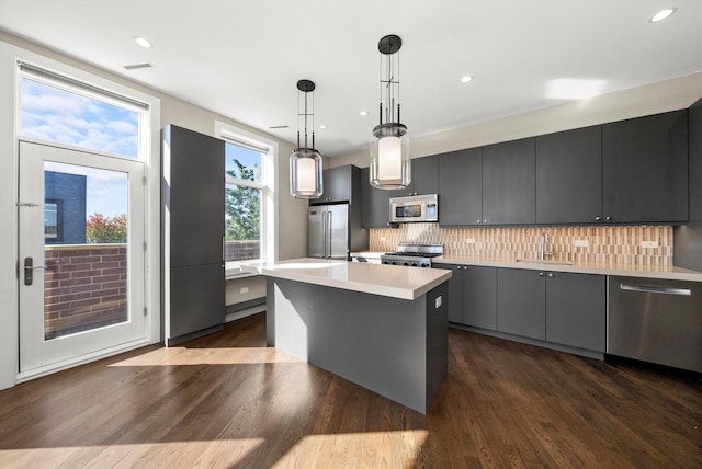 kitchen with dark wood-style flooring, a sink, decorative backsplash, light countertops, and appliances with stainless steel finishes