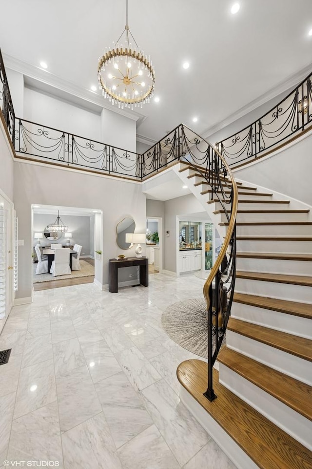 entryway with stairway, baseboards, an inviting chandelier, a towering ceiling, and marble finish floor