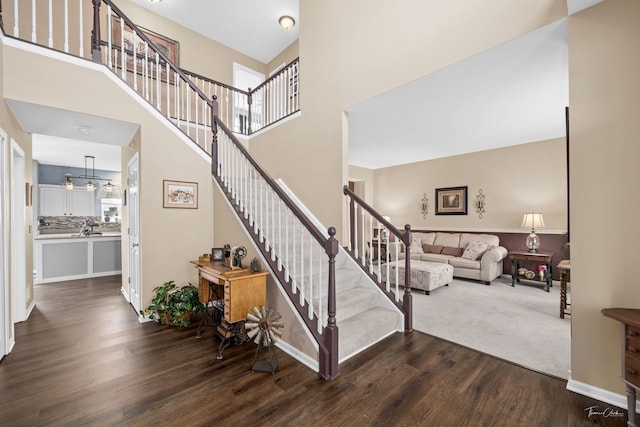 stairway featuring a high ceiling, baseboards, and wood finished floors