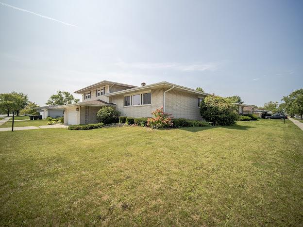 view of front facade featuring a garage, brick siding, and a front yard