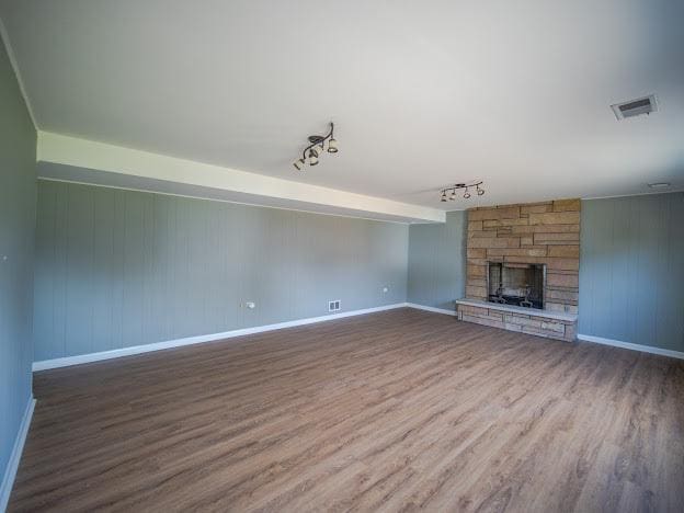 unfurnished living room with visible vents, a fireplace, and wood finished floors