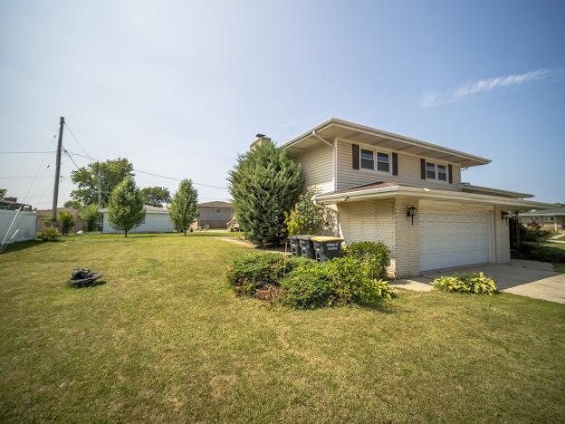 exterior space with brick siding, an attached garage, concrete driveway, and a front lawn