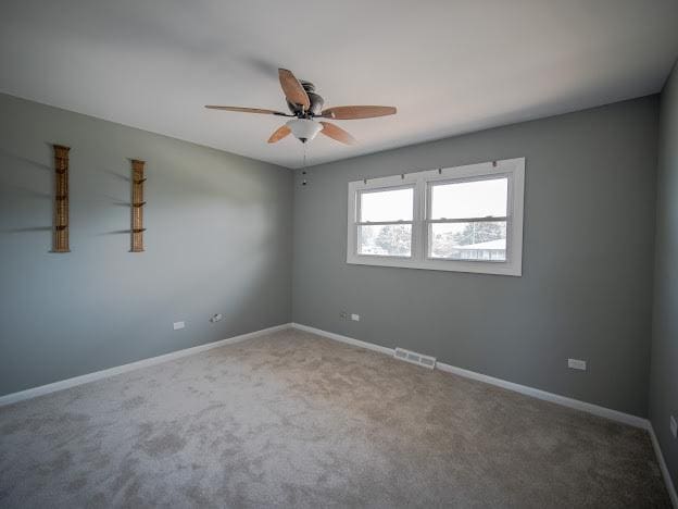 unfurnished room with visible vents, carpet flooring, baseboards, and ceiling fan