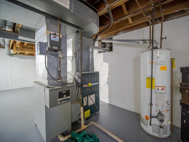 utility room featuring heating unit and water heater