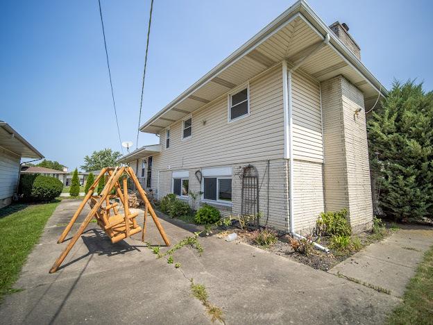 rear view of property with a playground and a chimney