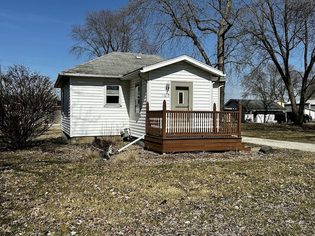 view of front of home with a wooden deck and roof with shingles