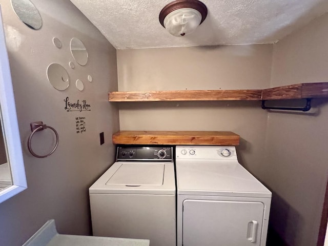 washroom featuring washing machine and clothes dryer, laundry area, and a textured ceiling