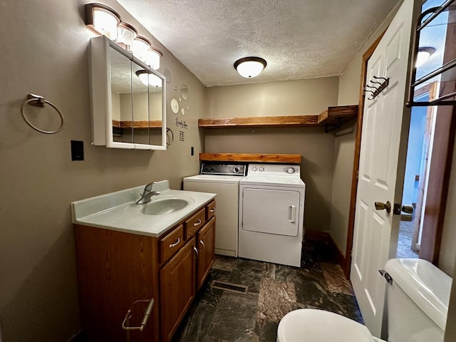 bathroom featuring washer and dryer, a textured ceiling, toilet, and vanity