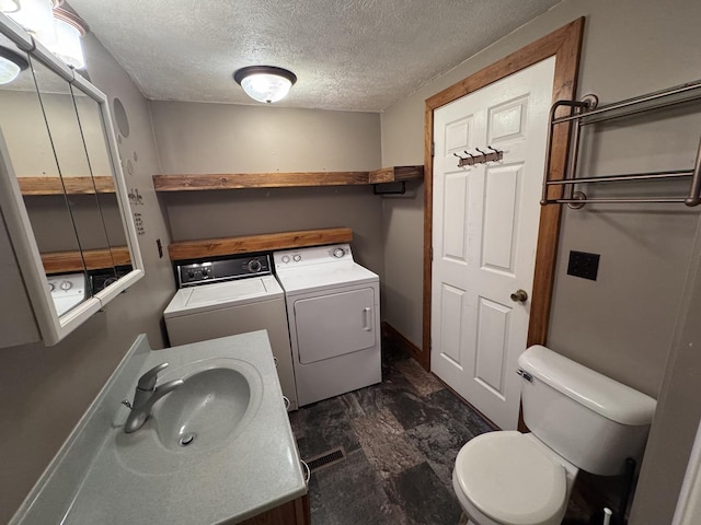 bathroom featuring vanity, visible vents, a textured ceiling, washer and dryer, and toilet