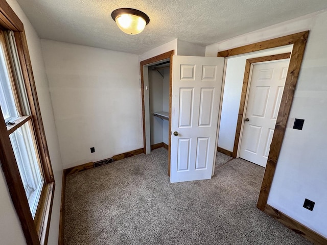 unfurnished bedroom featuring carpet flooring, visible vents, a textured ceiling, and baseboards