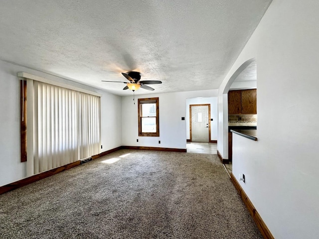 spare room featuring visible vents, baseboards, carpet flooring, arched walkways, and a textured ceiling