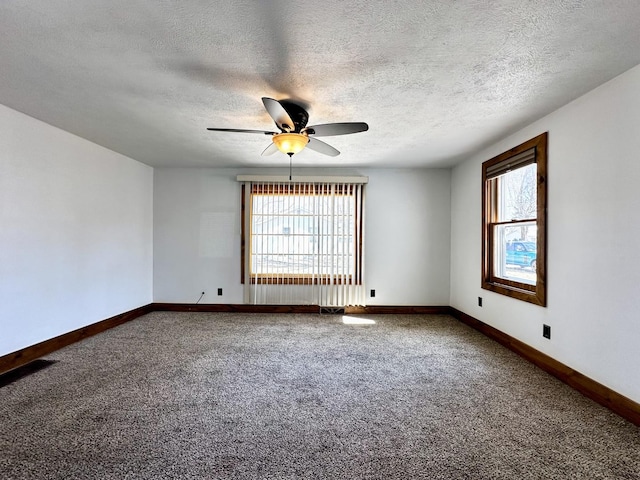 carpeted spare room featuring baseboards, a textured ceiling, and a ceiling fan