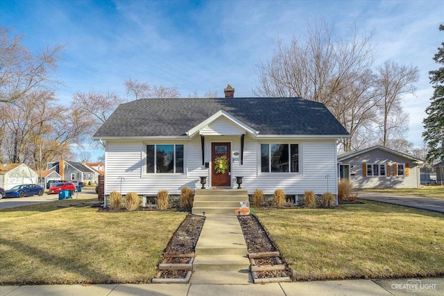 view of front of house featuring a chimney, a front yard, and roof with shingles