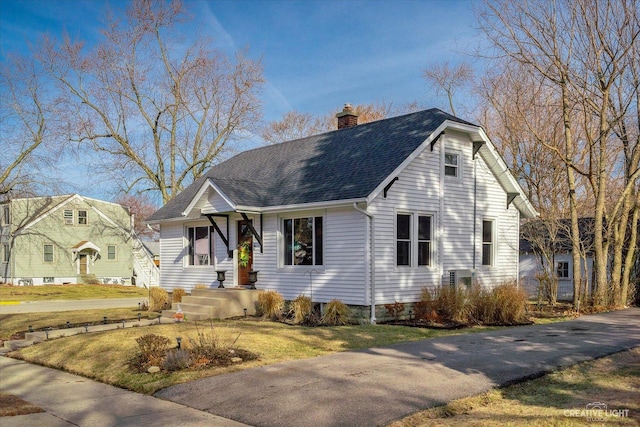 view of front of house featuring a front lawn, a chimney, and roof with shingles