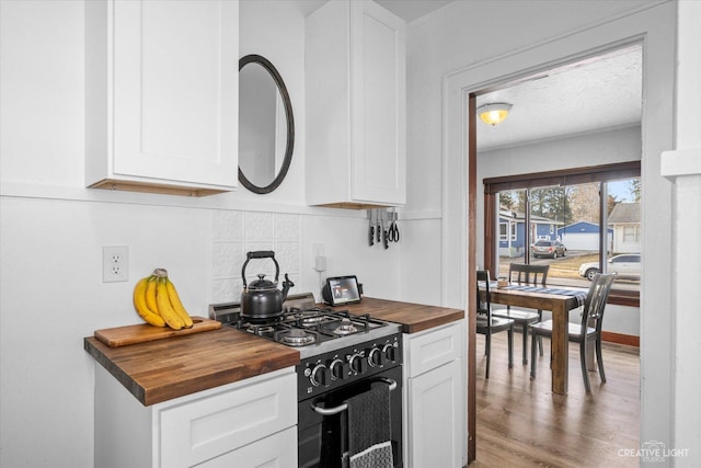 kitchen with white cabinets, black range with gas cooktop, and butcher block counters