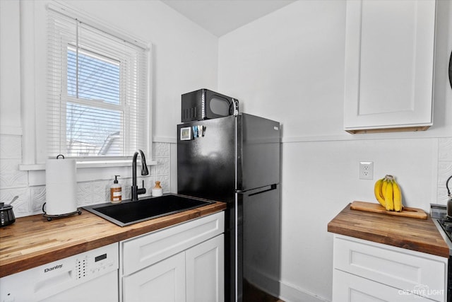 kitchen with a sink, black appliances, white cabinetry, and butcher block countertops