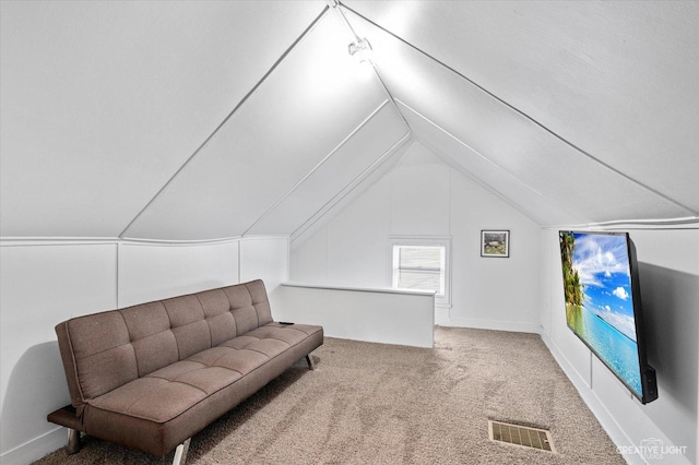 sitting room featuring visible vents, lofted ceiling, and carpet