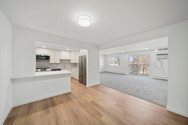 kitchen with tasteful backsplash, a baseboard heating unit, light countertops, stainless steel appliances, and white cabinetry