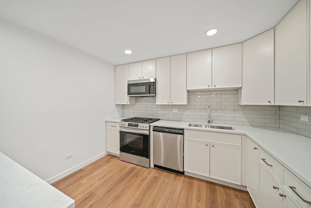 kitchen featuring a sink, decorative backsplash, appliances with stainless steel finishes, and light wood-style flooring