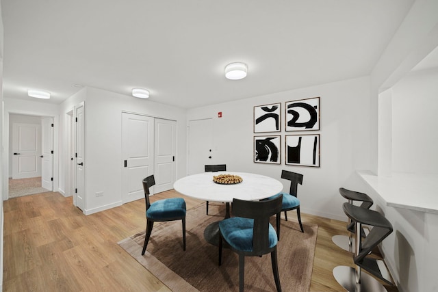 dining area featuring light wood-style flooring and baseboards