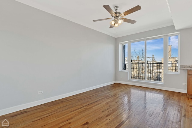 unfurnished room with ceiling fan, crown molding, baseboards, and hardwood / wood-style flooring