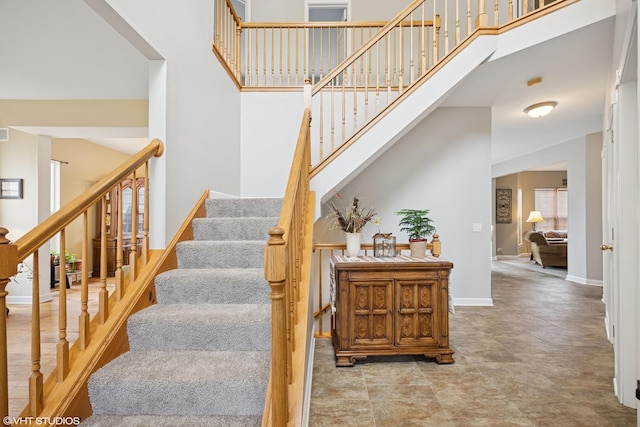 staircase with baseboards and a towering ceiling