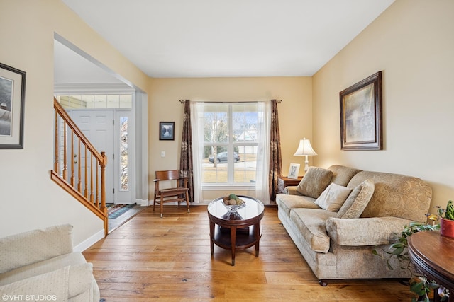 living area featuring stairs, light wood-type flooring, and baseboards