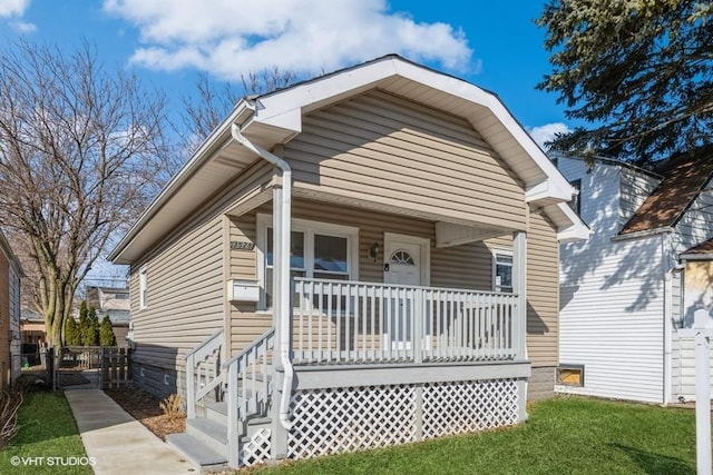 view of front of property with a porch, a front yard, and fence