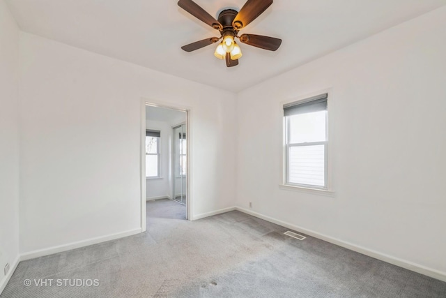 carpeted spare room featuring visible vents, baseboards, and a ceiling fan