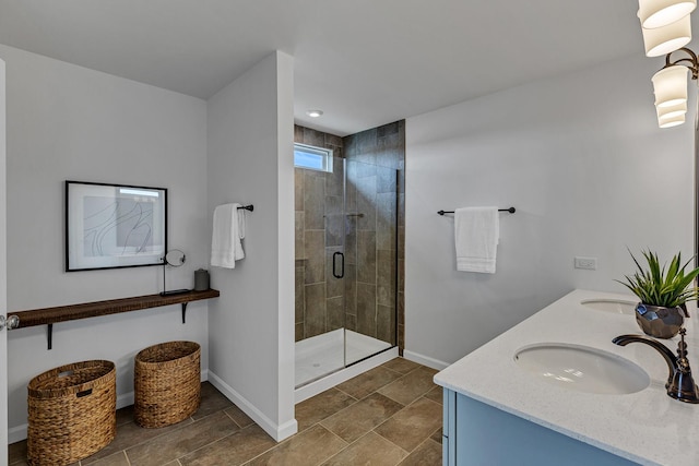 bathroom featuring double vanity, a shower stall, baseboards, and a sink