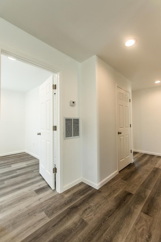 hall featuring visible vents, baseboards, and dark wood-style flooring