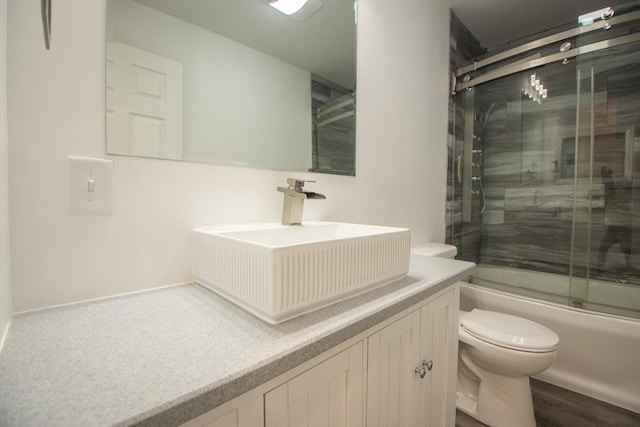 bathroom with vanity, toilet, and combined bath / shower with glass door