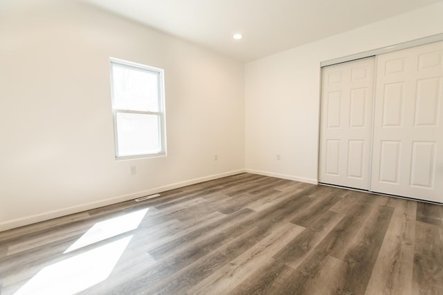 unfurnished bedroom featuring visible vents, wood finished floors, recessed lighting, a closet, and baseboards