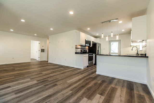 kitchen with stainless steel appliances, dark countertops, open floor plan, and white cabinets