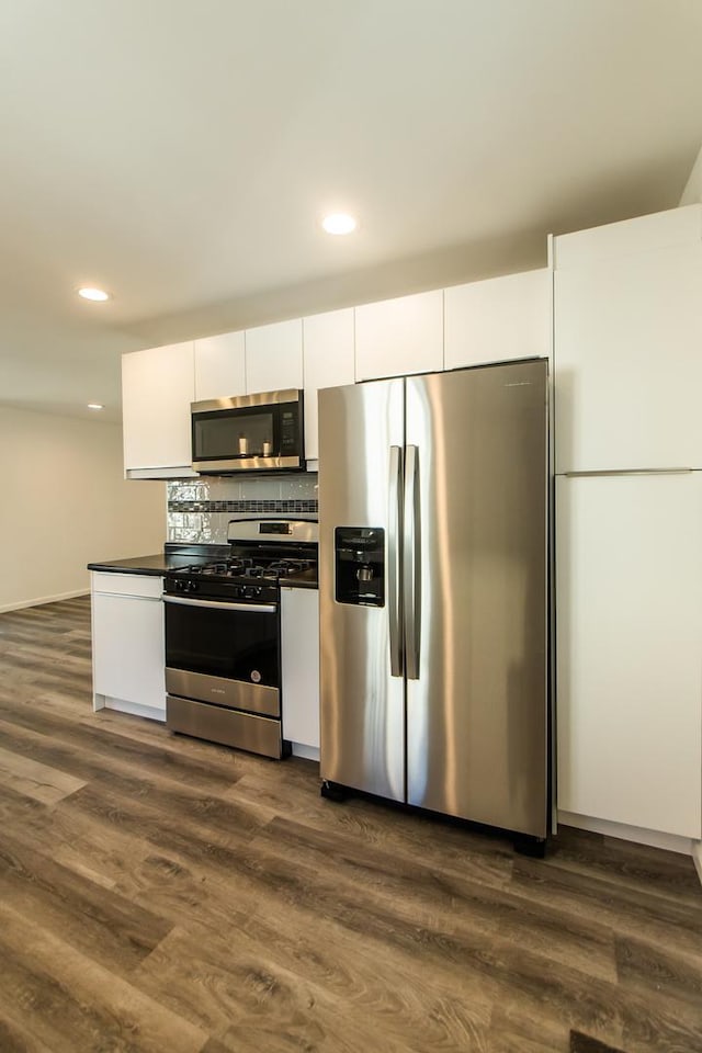 kitchen with dark countertops, white cabinets, dark wood-style floors, and stainless steel appliances