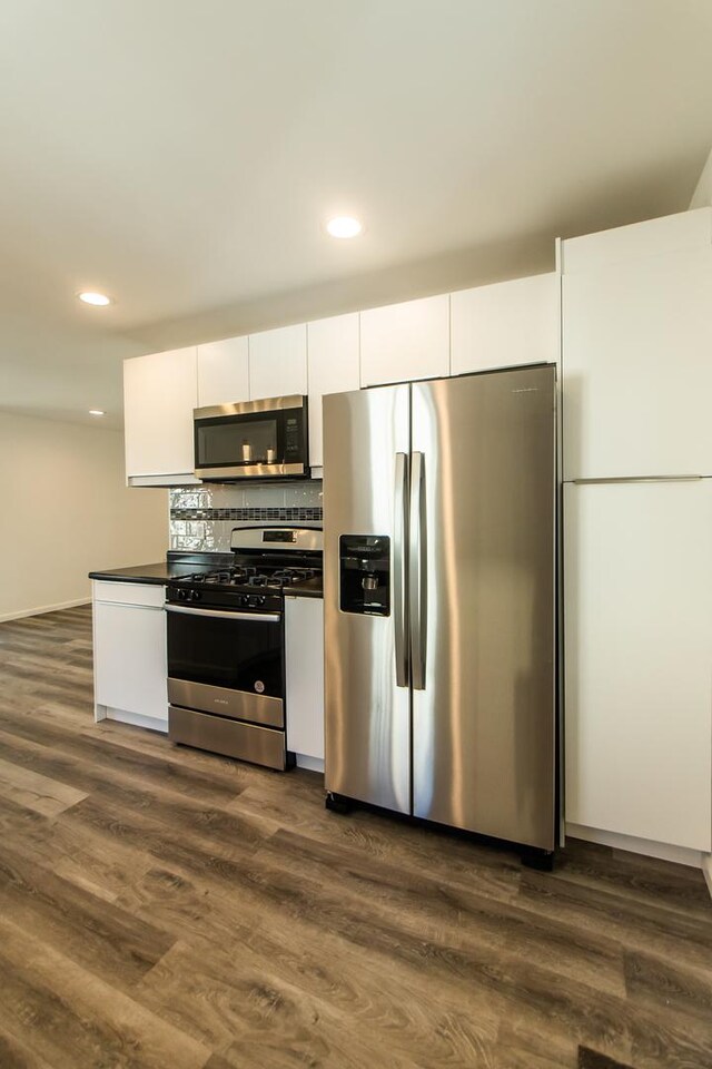 kitchen with dark countertops, a peninsula, open floor plan, and white cabinets