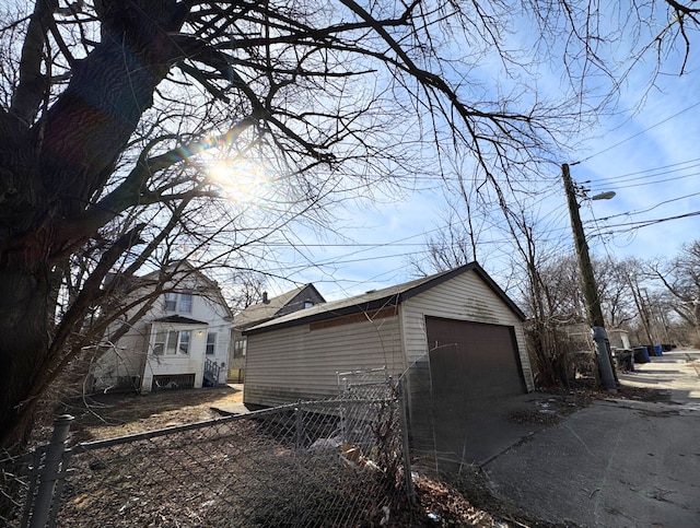 view of home's exterior with a detached garage, an outbuilding, fence, and driveway