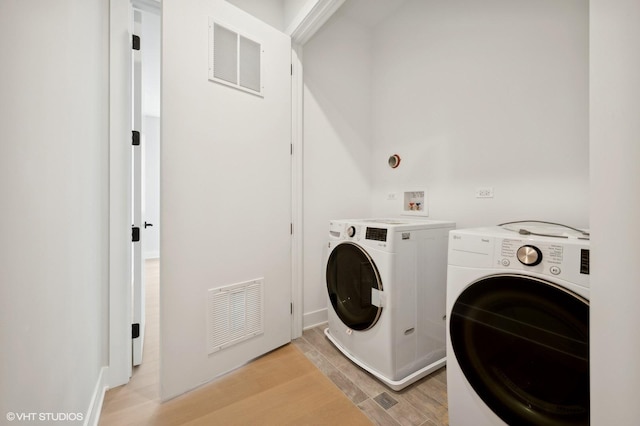 clothes washing area featuring visible vents, independent washer and dryer, laundry area, and light wood-style floors