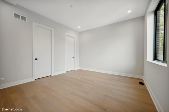 unfurnished room featuring a wealth of natural light, visible vents, and light wood-style flooring