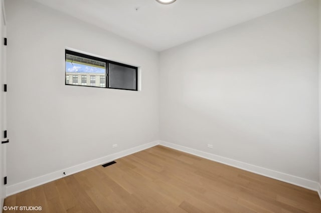 unfurnished room featuring light wood-type flooring, baseboards, and visible vents