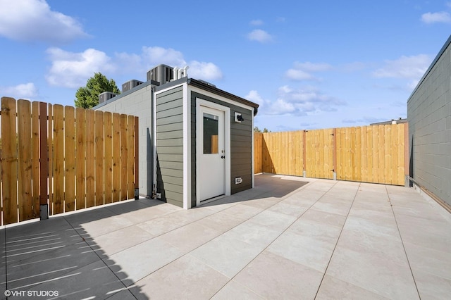 view of shed featuring a gate, fence, and cooling unit