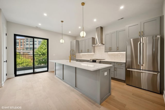 kitchen with tasteful backsplash, visible vents, wall chimney range hood, gray cabinets, and freestanding refrigerator