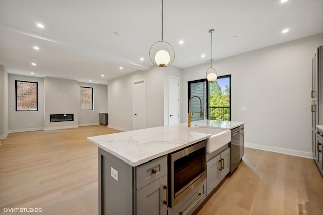 kitchen featuring a sink, light wood-style floors, gray cabinets, and stainless steel appliances