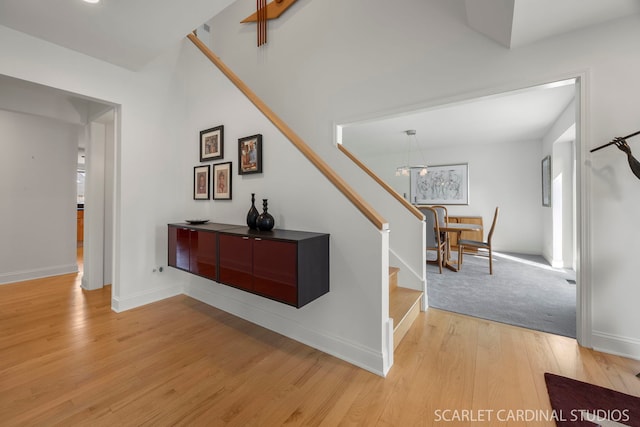 stairs with baseboards, a notable chandelier, and wood finished floors