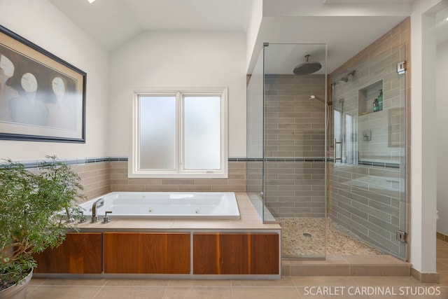 full bath with a shower stall, vaulted ceiling, a tub with jets, and tile patterned flooring